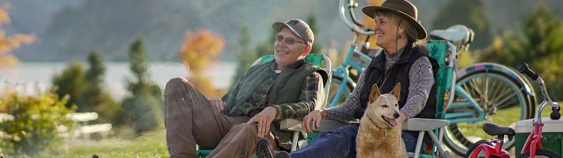 Elderly man and woman sitting outside with their dog