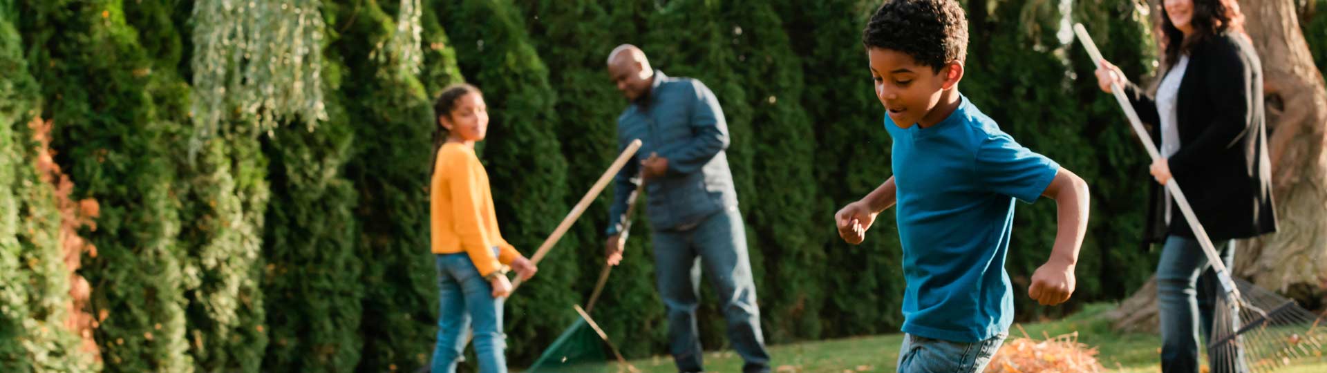 Family of four outside racking fall leaves